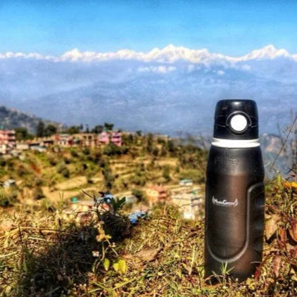 Gourde filtrante HumaGreen sur un paysage de montagne avec des sommets enneigés en arrière-plan